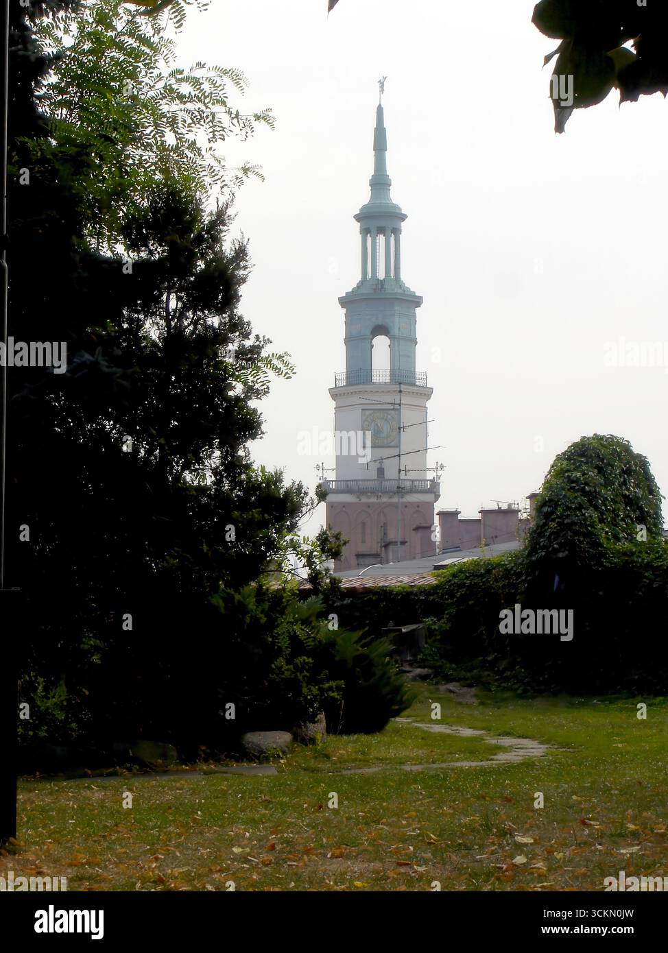 Durch einen üppigen Park in Posen schlängelt sich ein beschaulicher Pfad, der von Grün gesäumt ist, während der historische Rathausturm majestätisch im Hintergrund aufragt Stockfoto Durch einen üppigen Park in Posen schlängelt sich ein beschaulicher Pfad, der von Grün gesäumt ist, während der historische Rathausturm majestätisch im Hintergrund aufragt Stockfoto