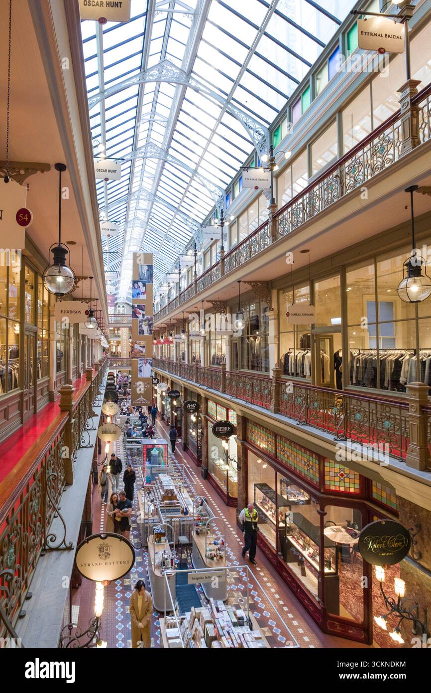 Eine geschäftige Einkaufspassage mit eleganter Architektur, voller Geschäfte, Boutiquen und Besuchern, die ihr Einkaufserlebnis genießen. Die Strand Arcade Stockfoto