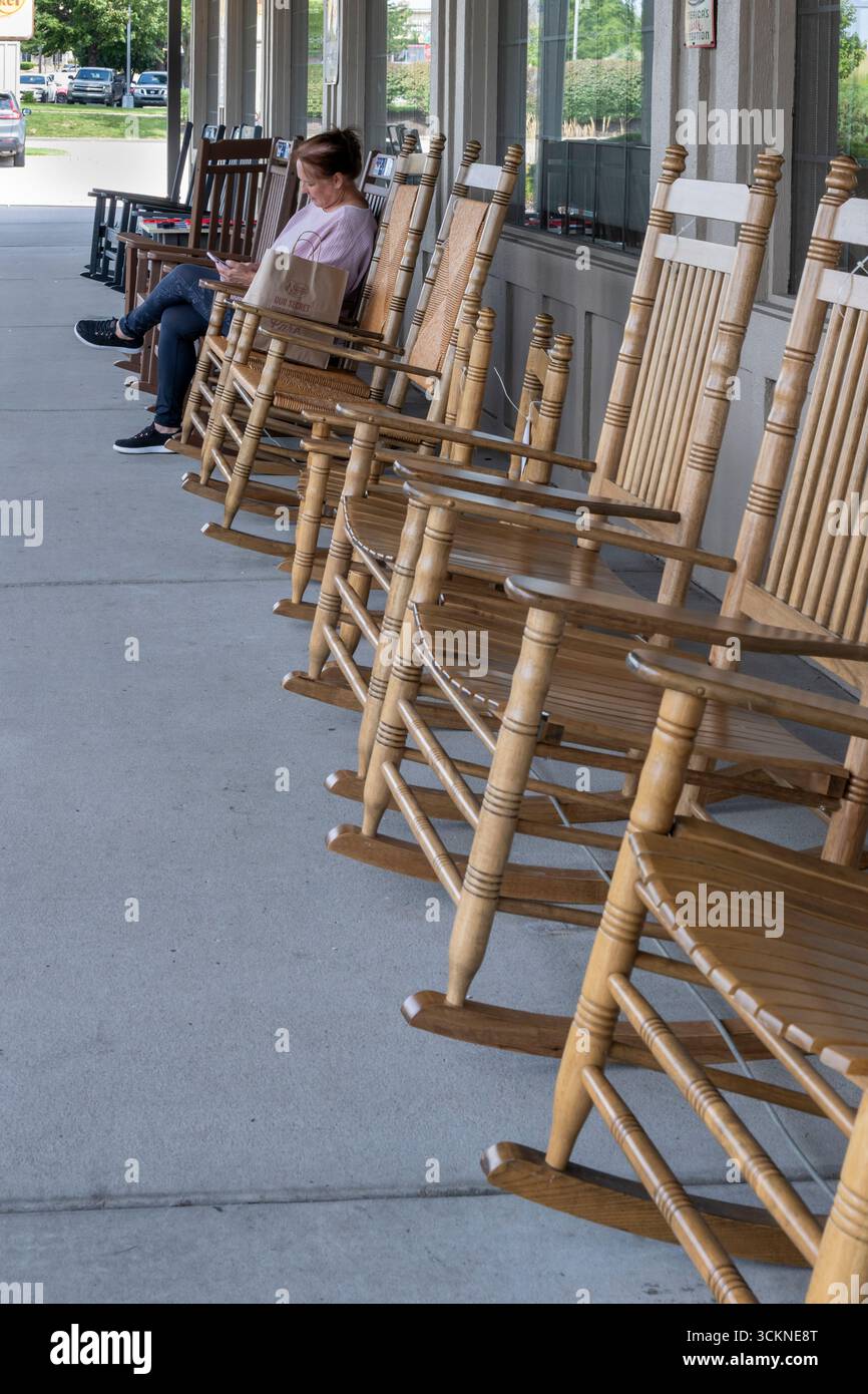 Olathe, Kansas. Frau mit Telefon im Schaukelstuhl auf der Ladenfront des Cracker Barrel Restaurants mit seiner gutbürgerlichen Landküche und g Stockfoto