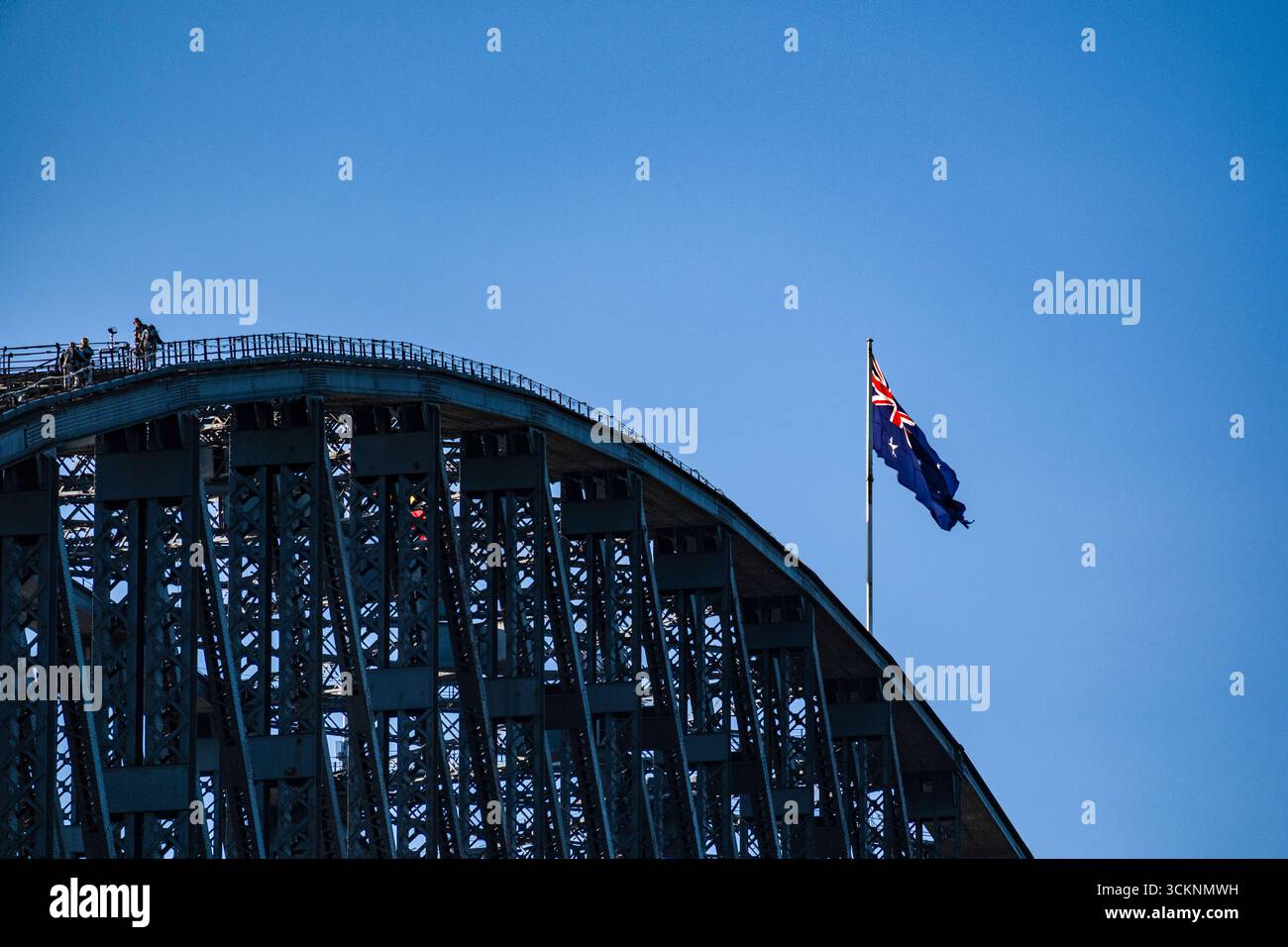 Die berühmte Sydney Harbour Bridge wurde mit der australischen Flagge besetzt, die deutlich darüber schwenkt und sowohl Nationalstolz als auch architektonische Größe symbolisiert Stockfoto