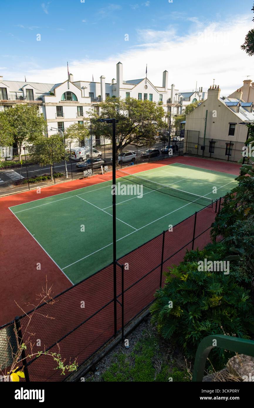 Ein lebhafter Tennisplatz im Freien in einem Stadtgebiet, umgeben von modernen Gebäuden, üppigem Grün und einem sonnigen, blauen Himmel, Sydney Stockfoto