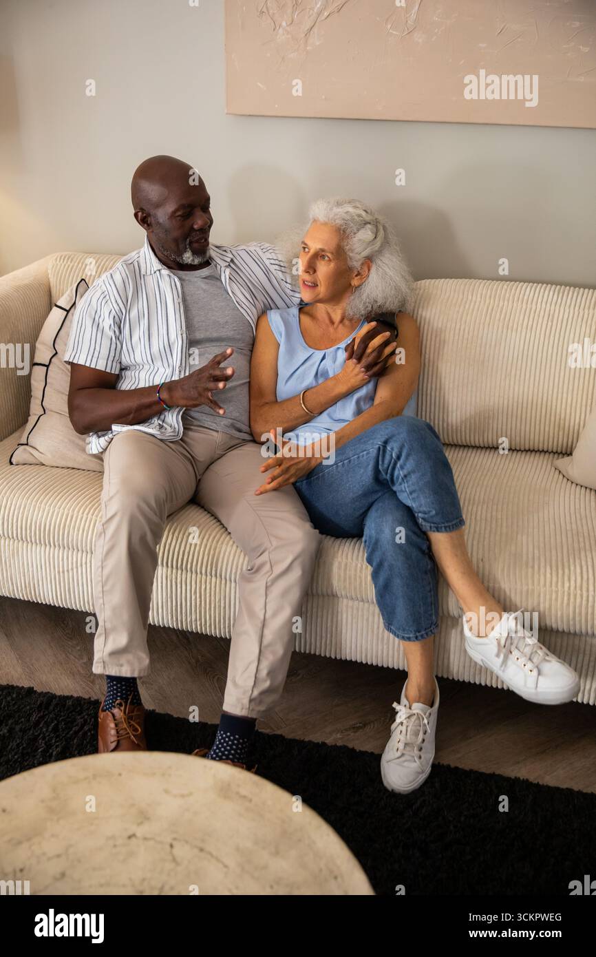 Verschiedene Seniorenpaare sitzen zu Hause auf Cordsofa und unterhalten sich über Smartphone neben Marmortisch Stockfoto