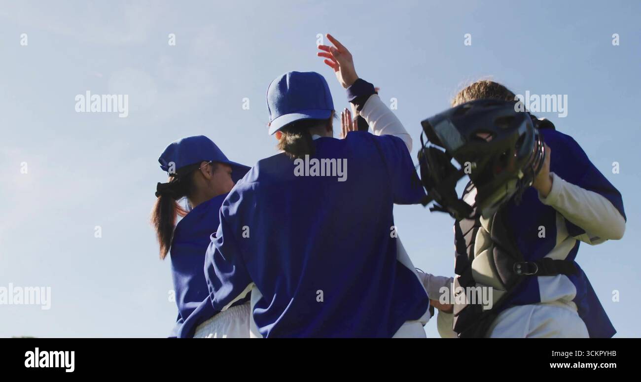 Baseballspielerinnen mit blauen Trikots und Kappen auf dem sonnigen Feld, mit Fangausrüstung Stockfoto