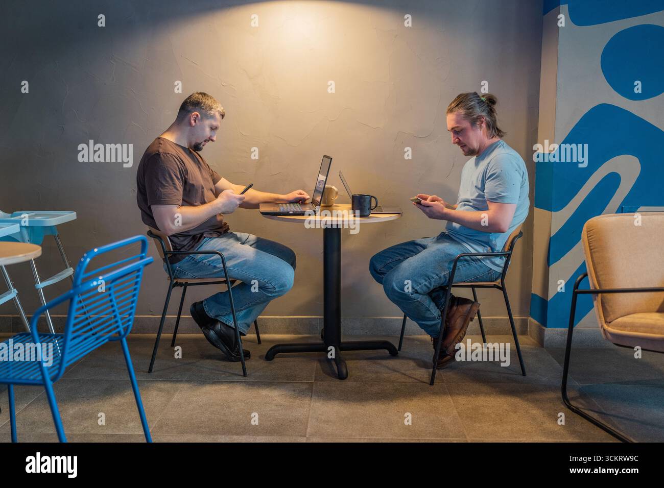 Zwangloses Meeting im modernen Café. Team von Programmierern, die digitalen Code in der Metaverse schreiben und zusammenarbeiten Stockfoto