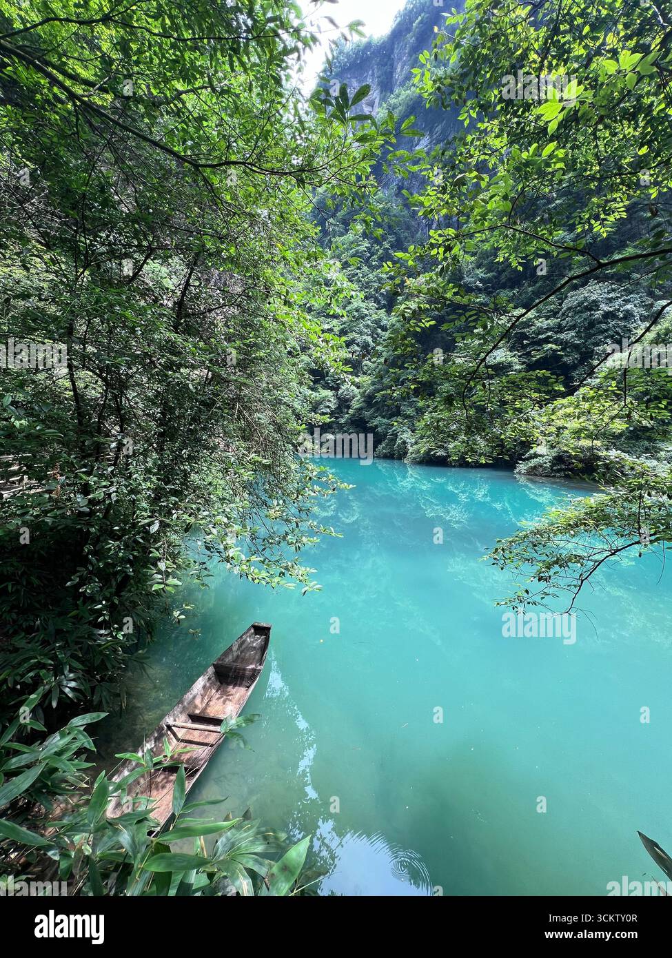 Ein hölzernes Boot auf türkisfarbenem Wasser, eine perfekte Kulisse für Ruhe und zeitlose Schönheit. Stockfoto