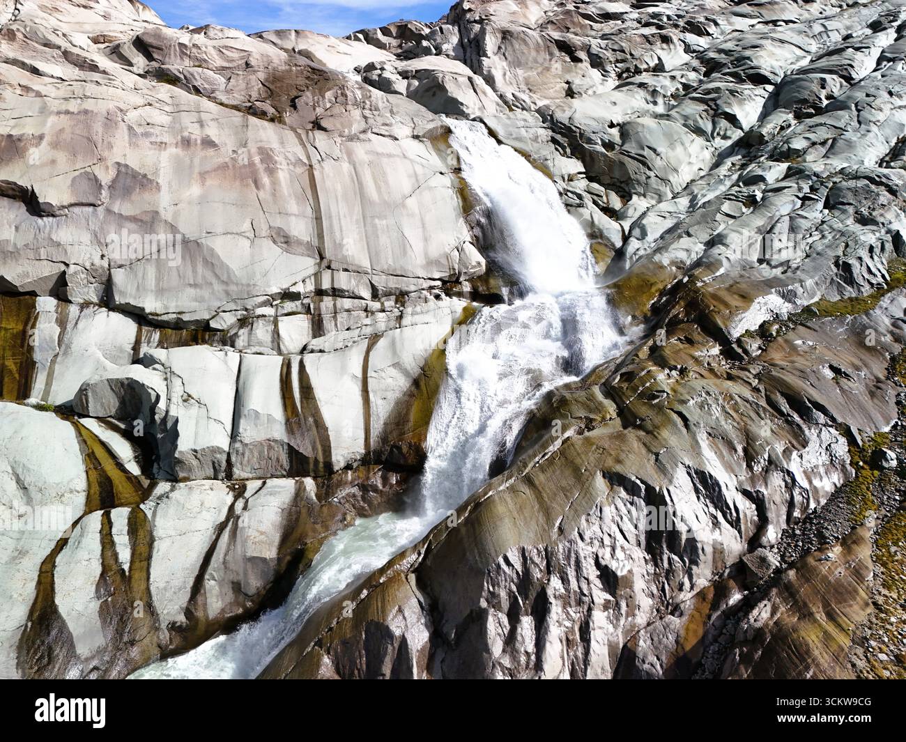 Wasserfall am Rhonegletscher – Blick aus der Vogelperspektive auf das Gletschermelzwasser in den Schweizer Alpen Stockfoto