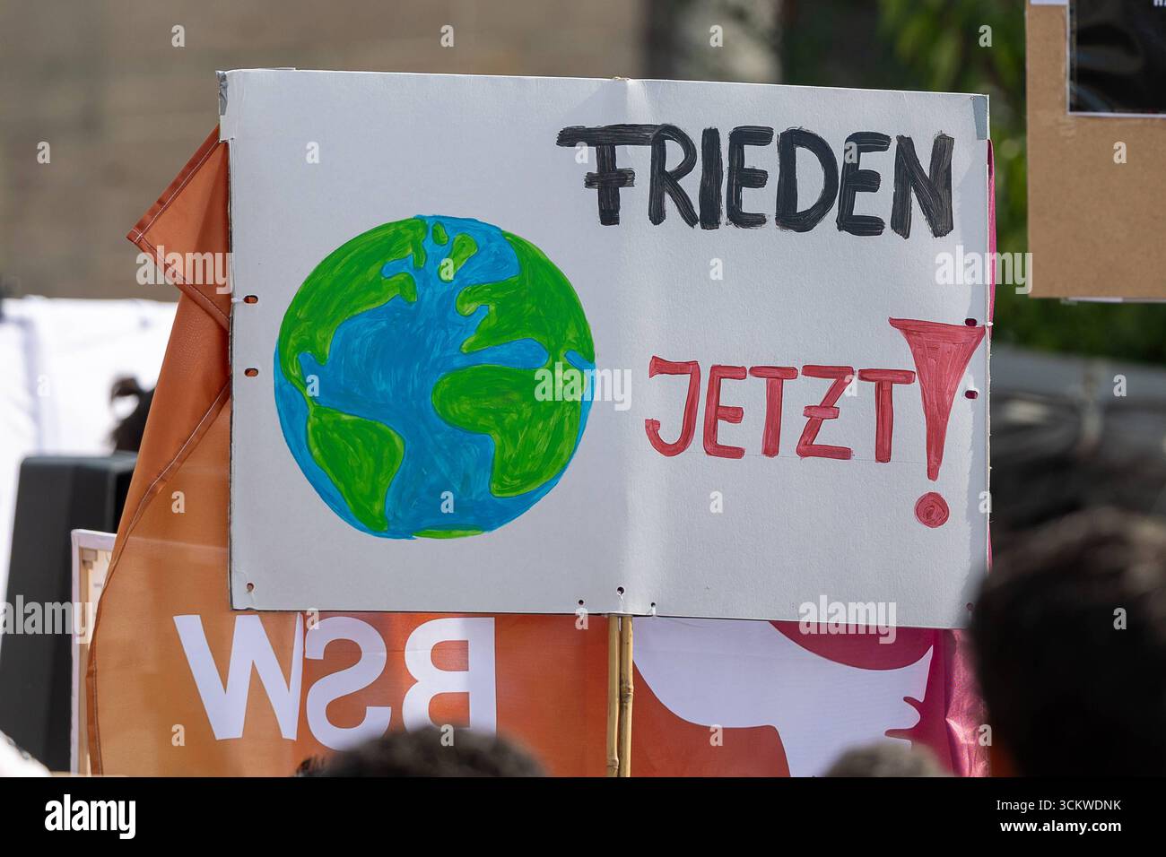 Pro-palästinensische Kundgebung mit Protestmarsch durch Nürnbergs Innenstadt, Nürnberg, 13.09.2025 ein selbst gestaltetes Plakat mit der Aufschrift FRIEDEN JETZT und einer gemalten Weltkugel wird bei einer pro-palästinensischen Kundgebung auf dem Kornmarkt in Nürnberg hochhalten. Das Schild befindet sich über einem orangen transparent mit dem Logo der Partei Bündnis Sahra Wagenknecht BSW. Im Vordergrund sind Umrisse von Teilnehmern der Demonstration zu sehen. Nürnberg Altstadt - Saint Lorenz Bayern Deutschland *** pro-palästinensische Kundgebung mit protestmarsch durch Nürnberg Stadtzentrum, Nürnberg Stockfoto