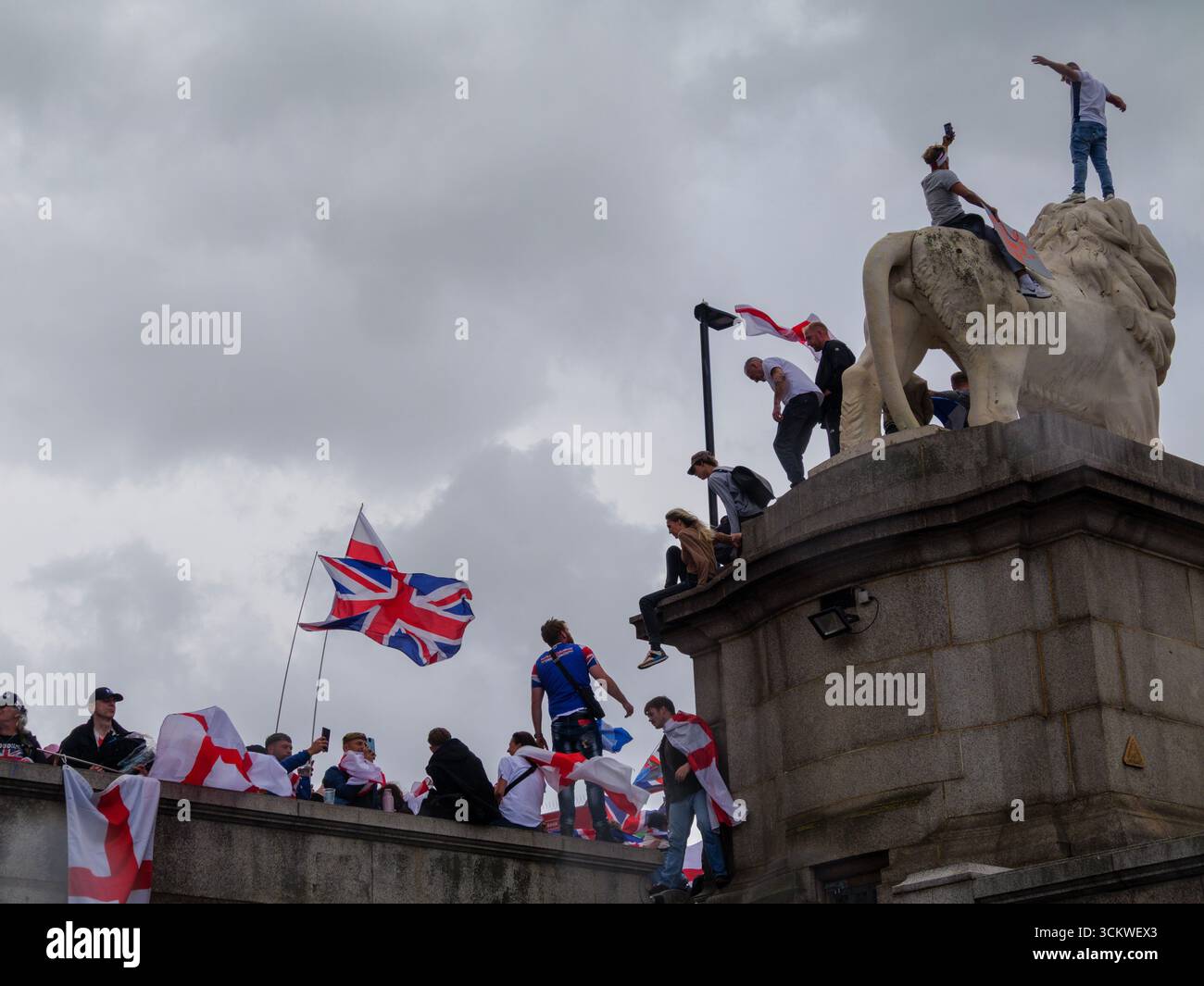 Unite the Kingdom Protest, 13. September 2025, Westminster, London, Großbritannien. Demonstranten mit Union Jack und St George's Flaggen klettern auf dem South Bank Lion auf der Westminster Bridge in Central London bei einem von Tommy Robinson organisierten Protest Stockfoto