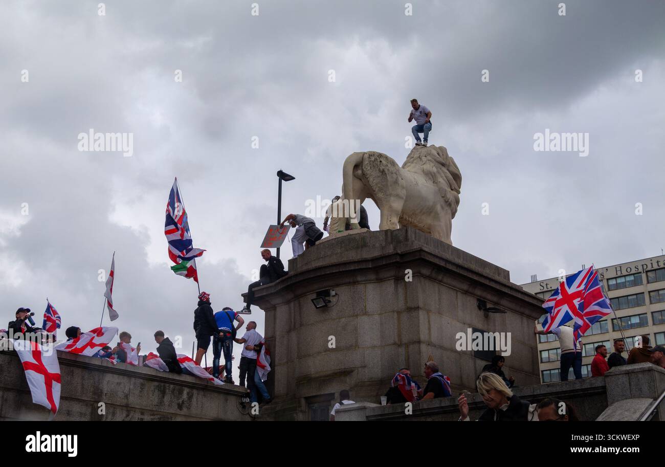 Unite the Kingdom Protest, 13. September 2025, Westminster, London, Großbritannien. Demonstranten mit Union Jack und St George's Flaggen klettern auf dem South Bank Lion auf der Westminster Bridge in Central London bei einem von Tommy Robinson organisierten Protest Stockfoto
