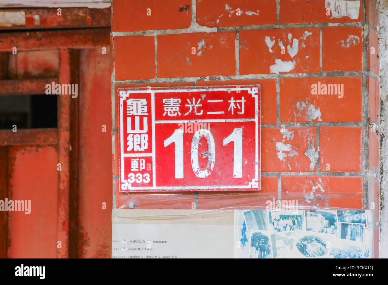 Taoyuan City, Taiwan - 01. Juni 2012: Ein rot-weißes Vintage-Gebäude mit der Nummer 101, das an einer verwitterten Ziegelwand mit abblätternder Farbe angebracht ist. Xian Guan Stockfoto