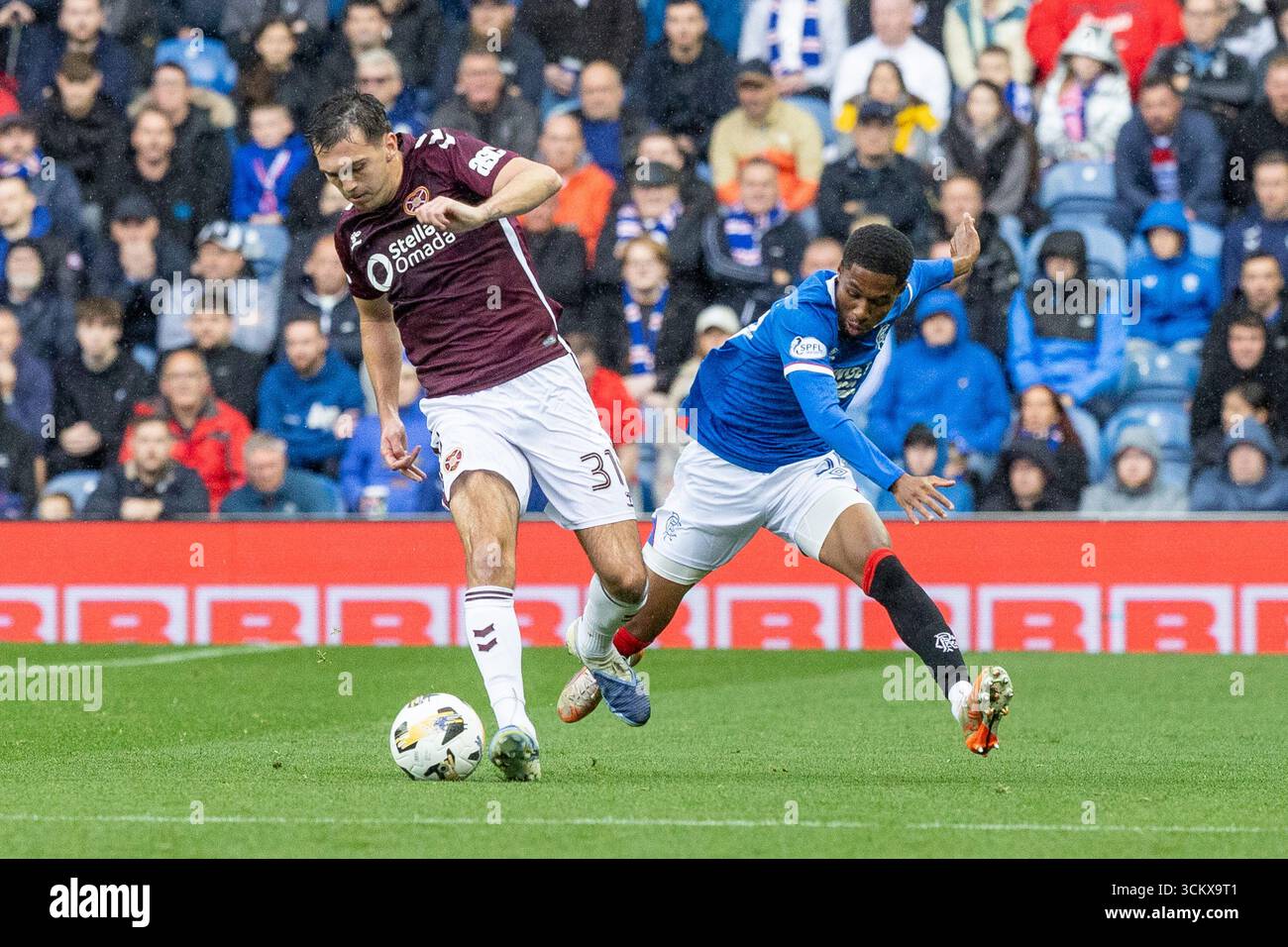 13. September 2025. Glasgow, Großbritannien. Die Rangers spielten Heart of Midlothian (Hearts) in einem Premiership-Spiel im Ibrox Stadium, Glasgow, Großbritannien. Das Ergebnis war die Rangers 0 - 2 Hearts of Midlothian. Jayden Meghoma (R30) und Oisin McEntee (H31) treten um den Ball an. Quelle: Findlay / Alamy Live News. Stockfoto