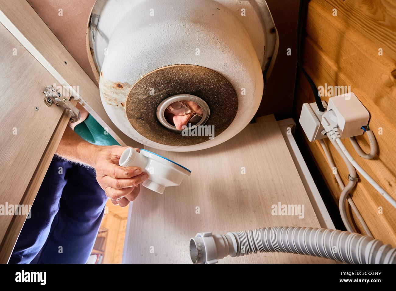 Küchenspüle Abflussinstallation, Klempner betrachtet den Kunststoff-Saitenhalter durch das Abflussloch in der Küchenspüle. Stockfoto