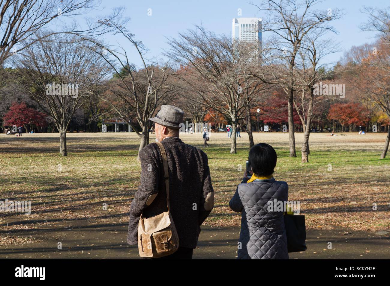 Ein älteres japanisches Paar hat einen Blick auf den Yoyogi Park mit dem Tokyo Opera City Tower in der Ferne. Tokio, Japan. Stockfoto