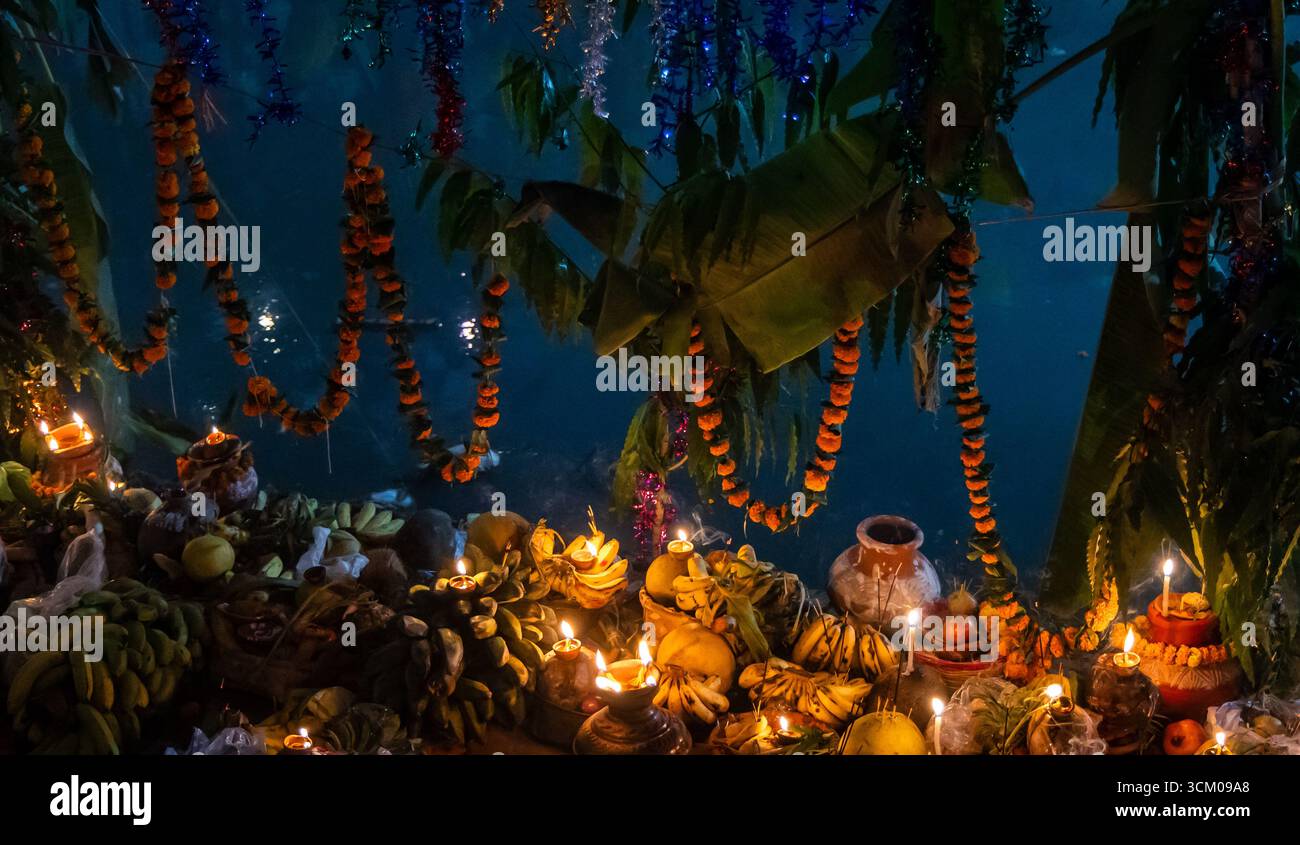 Heilige Chhath Puja daali mit Früchten, die mit traditioneller Öllampe am Ufer beleuchtet werden Stockfoto