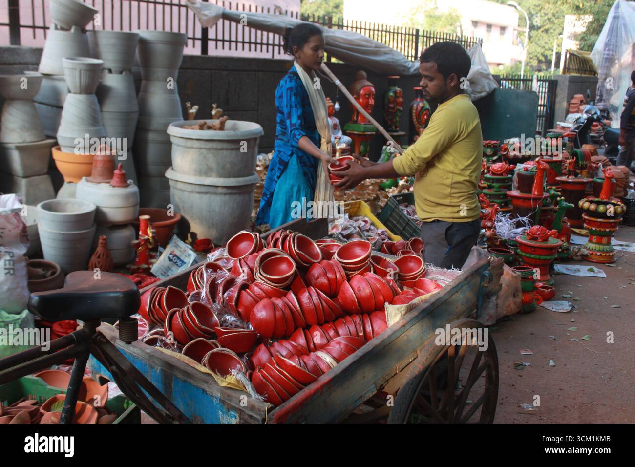 Ein Kutschenverkäufer übergibt irdene Töpfe an eine Frau auf dem Potters Market in Delhi, Indien. Stockfoto
