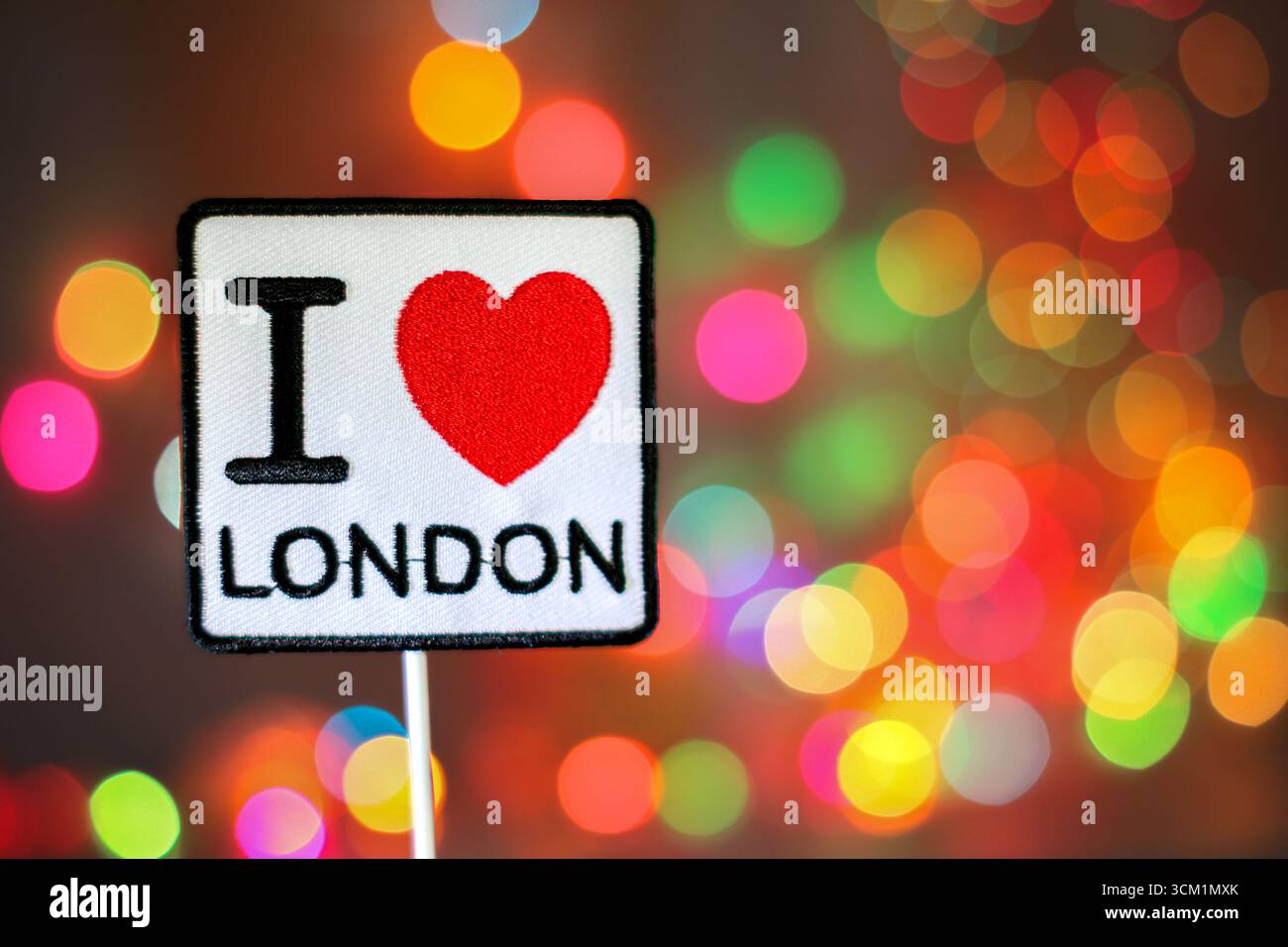 „I Love London“ mit gesticktem rotem Herz mit Regenbogenbokeh-Lichtern symbolisiert britischen Stolz, Feiertagsstimmung und festlichen Feierlichkeiten. Stockfoto
