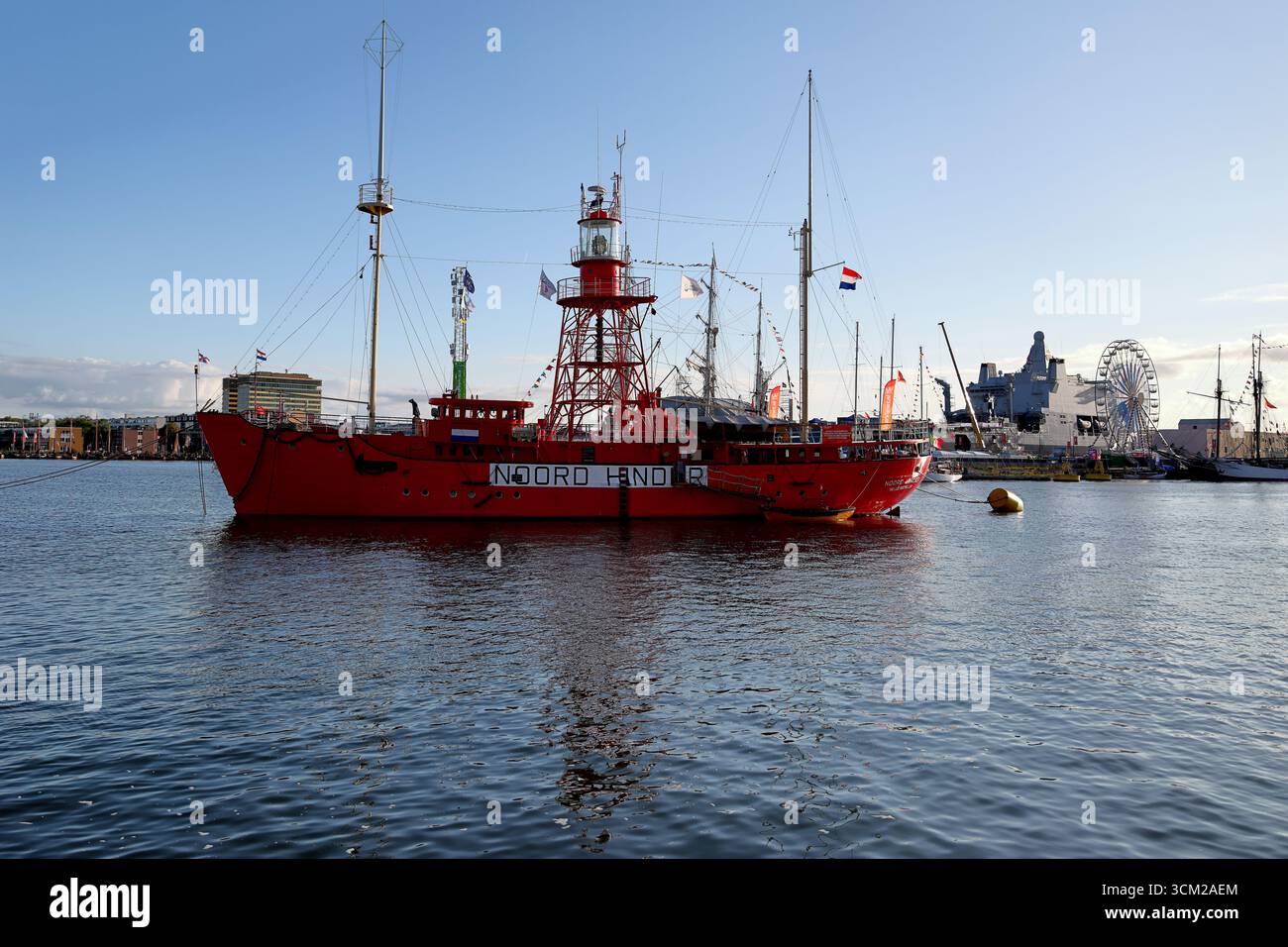 Lichtschip Noord hinder vertäut in Amsterdam, Niederlande während Sail 2025, hellrotes Leuchtschiff mit Gitterturm und Wasserreflexionen. Stockfoto