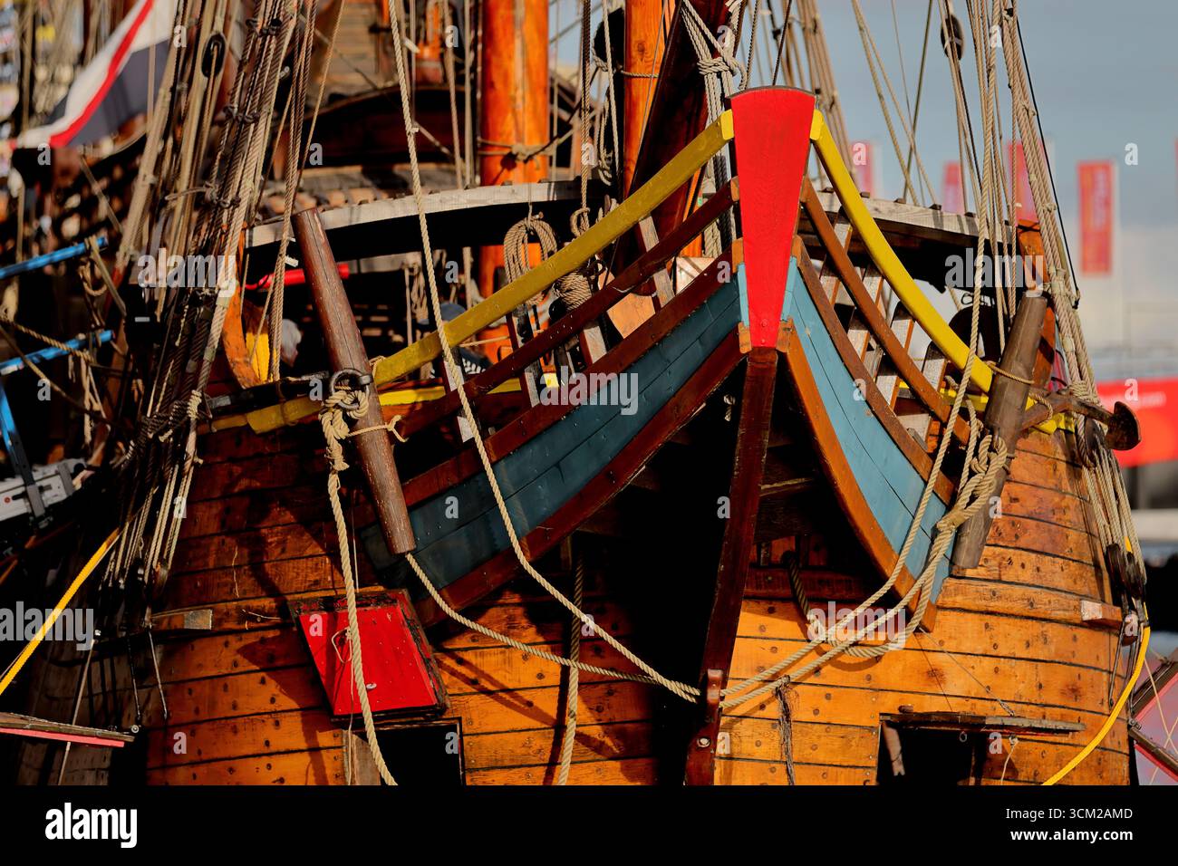 Nahaufnahme eines bunten Holzbogens mit Seilen und Beschlägen auf einem historischen Schiff, dokumentiert bei Sail 2025 in Amsterdam, Niederlande, warmer Abend. Stockfoto
