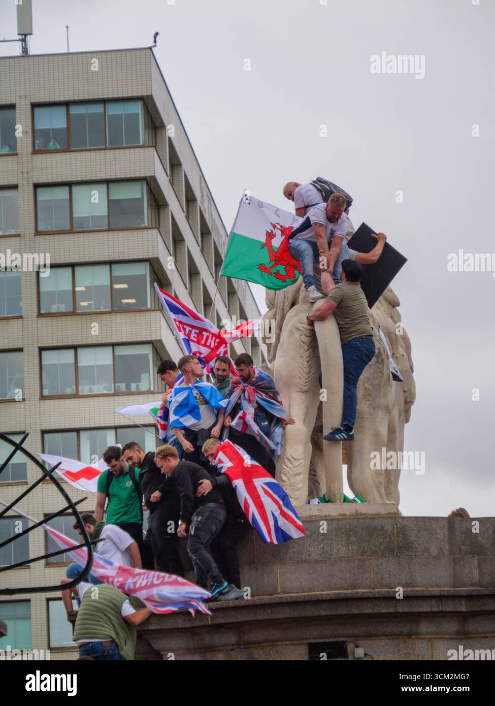 Unite the Kingdom Protest, 13. September 2025, Westminster, London, Großbritannien. Demonstranten mit Union Jack und St George's Flaggen klettern auf dem South Bank Lion auf der Westminster Bridge in Central London bei einem von Tommy Robinson organisierten Protest Stockfoto