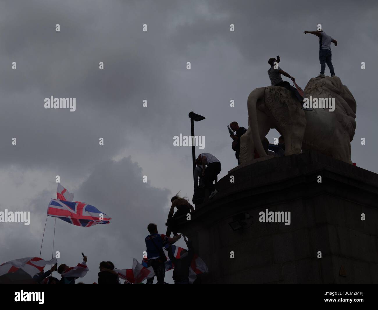 Unite the Kingdom Protest, 13. September 2025, Westminster, London, Großbritannien. Demonstranten mit Union Jack und St George's Flaggen klettern auf dem South Bank Lion auf der Westminster Bridge in Central London bei einem von Tommy Robinson organisierten Protest Stockfoto