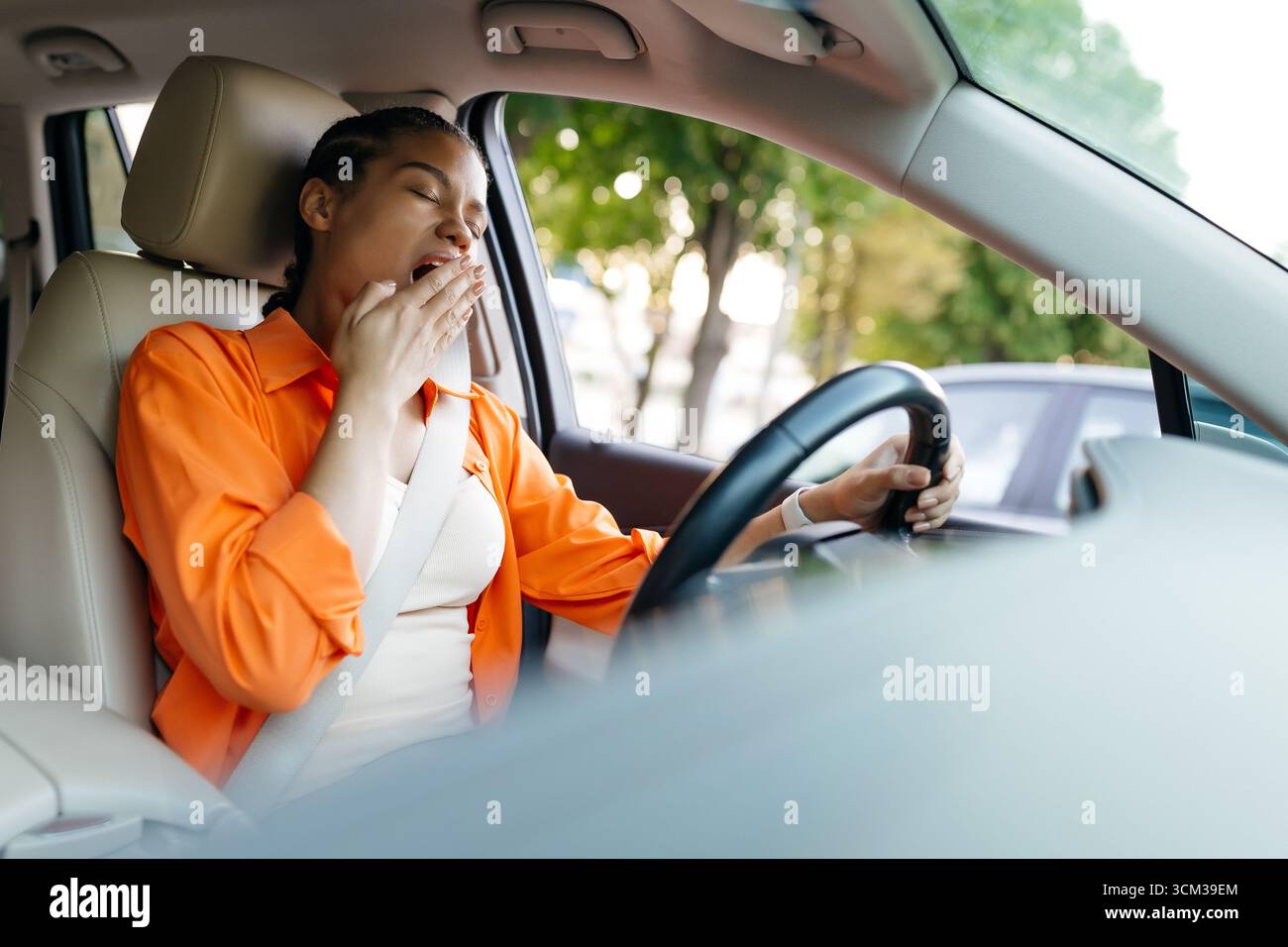 Müde afroamerikanische Frau gähnt beim Autofahren mit Sicherheitsgurt Stockfoto