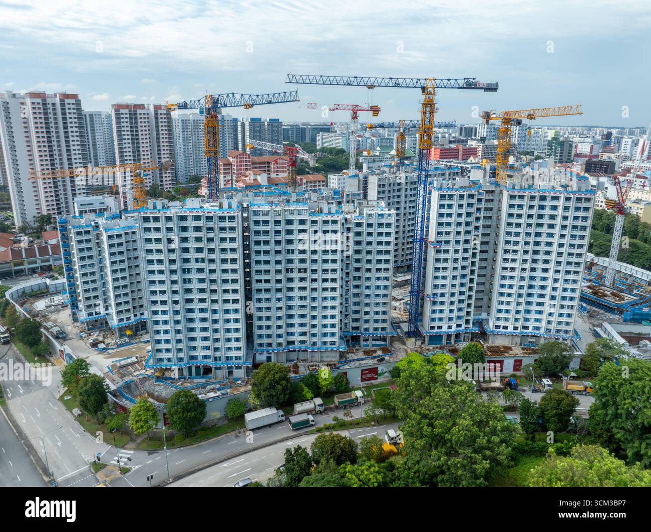 Blick aus der Vogelperspektive auf die glänzende, moderne Baustelle mit hochaufragenden Kränen vor dem Hintergrund städtischer Gebäude, Kallang, Singapur. Stockfoto