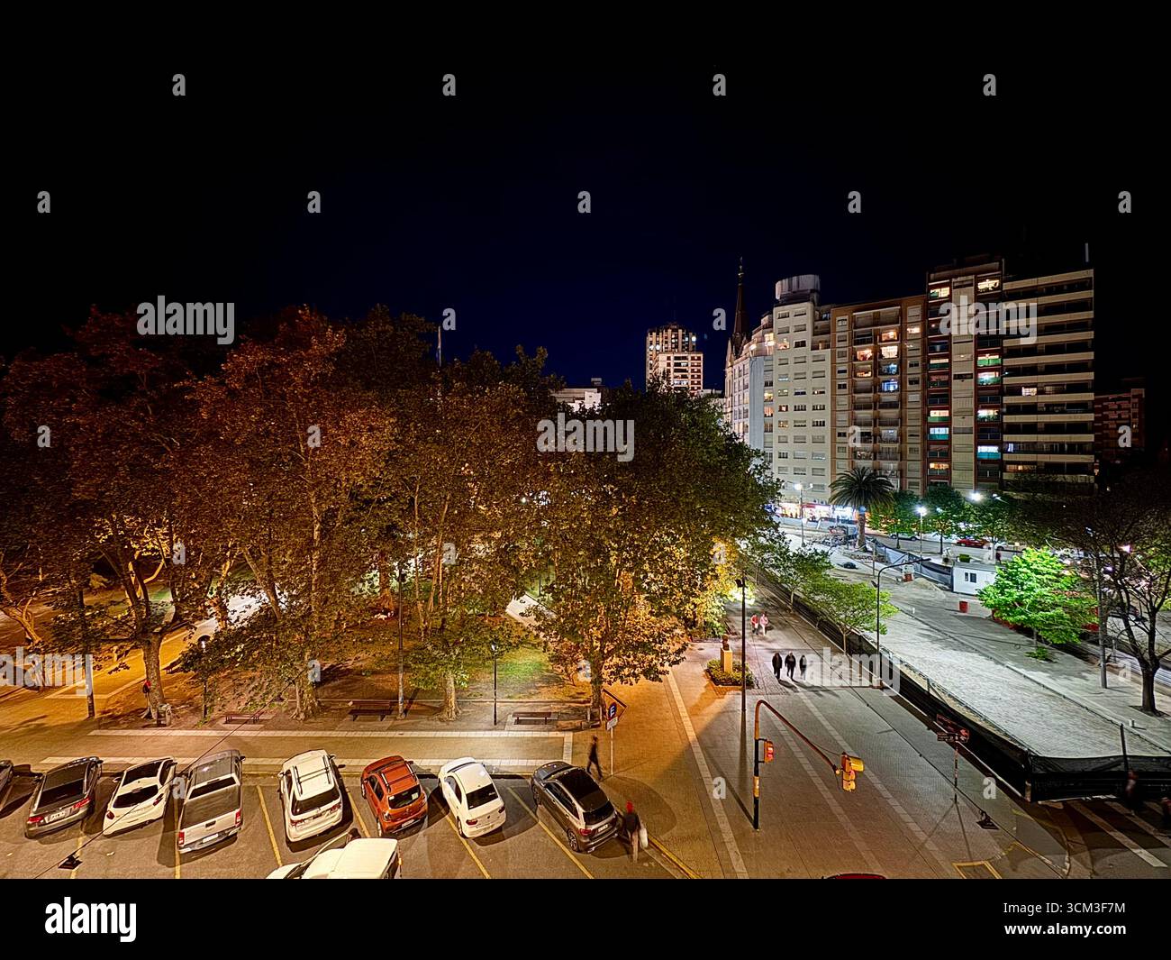 Mar del Plata - Nachtansicht auf einen Stadtplatz mit geparkten Autos und beleuchteten Gebäuden - Smartphone-aufgenommenes Stockfoto