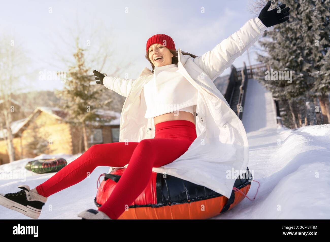 Frau genießt ein aufregendes Snowtubing-Erlebnis an einem Wintertag in einem Bergresort. Stockfoto