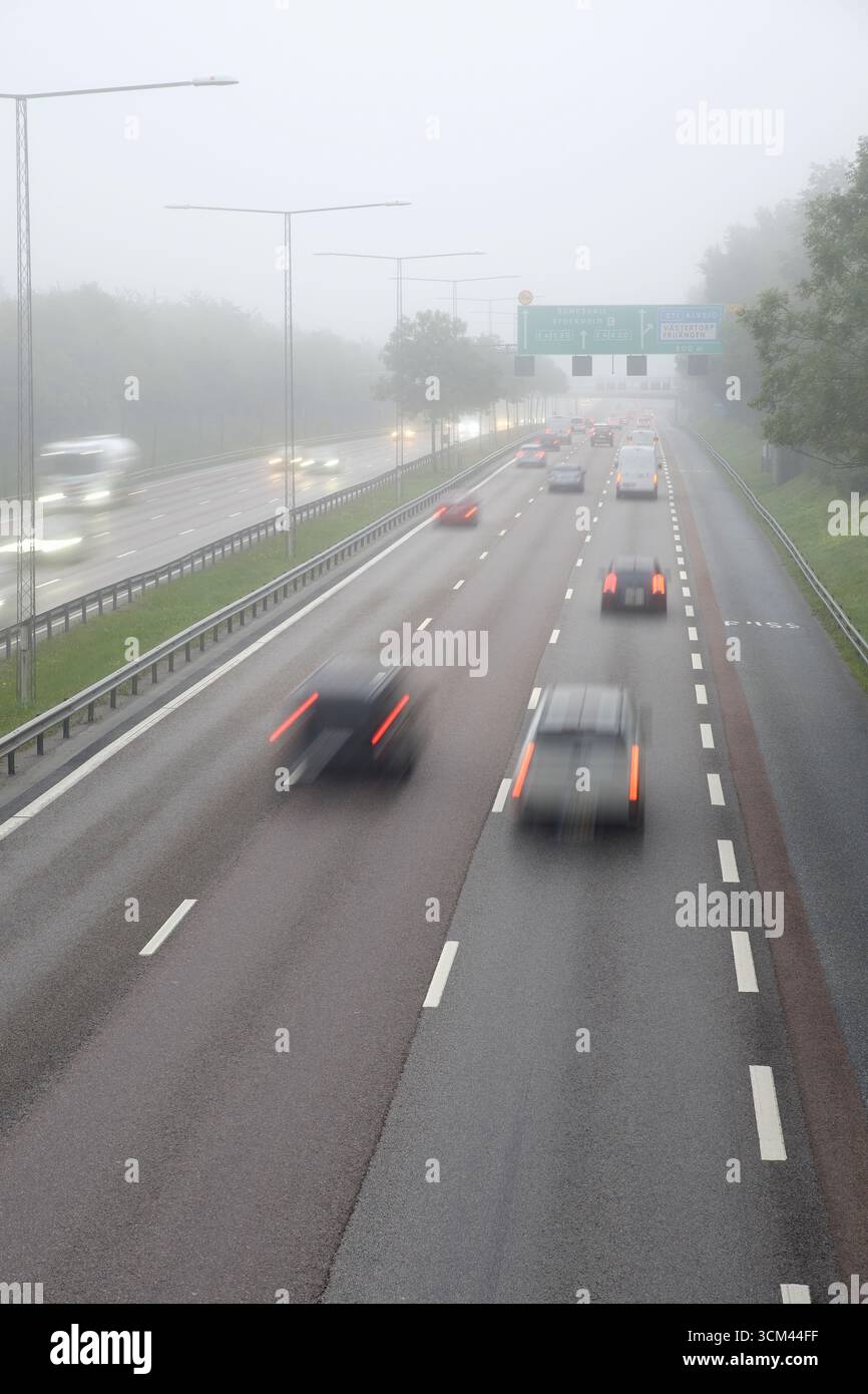Autos auf nebeliger Autobahn mit Straßenschildern in Richtung Sundsvall und Stockholm Stockfoto