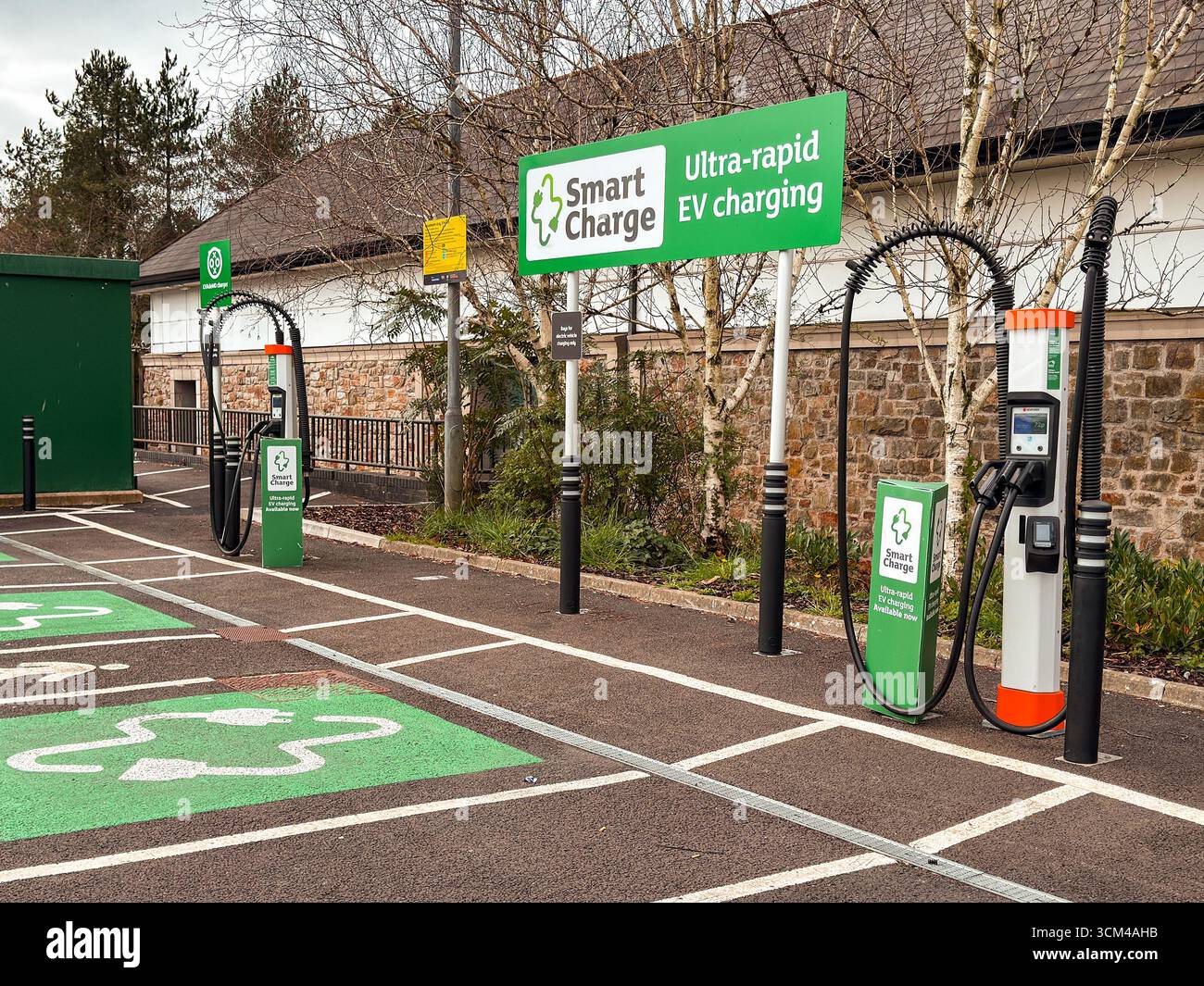 Bridgend, Wales, Vereinigtes Königreich - 26. März 2025: Parkbuchten mit Terminals zum Laden von Elektrofahrzeugen in einem Supermarkt-Parkplatz. Keine Personen. - Smartphone-aufgenommenes Stockfoto