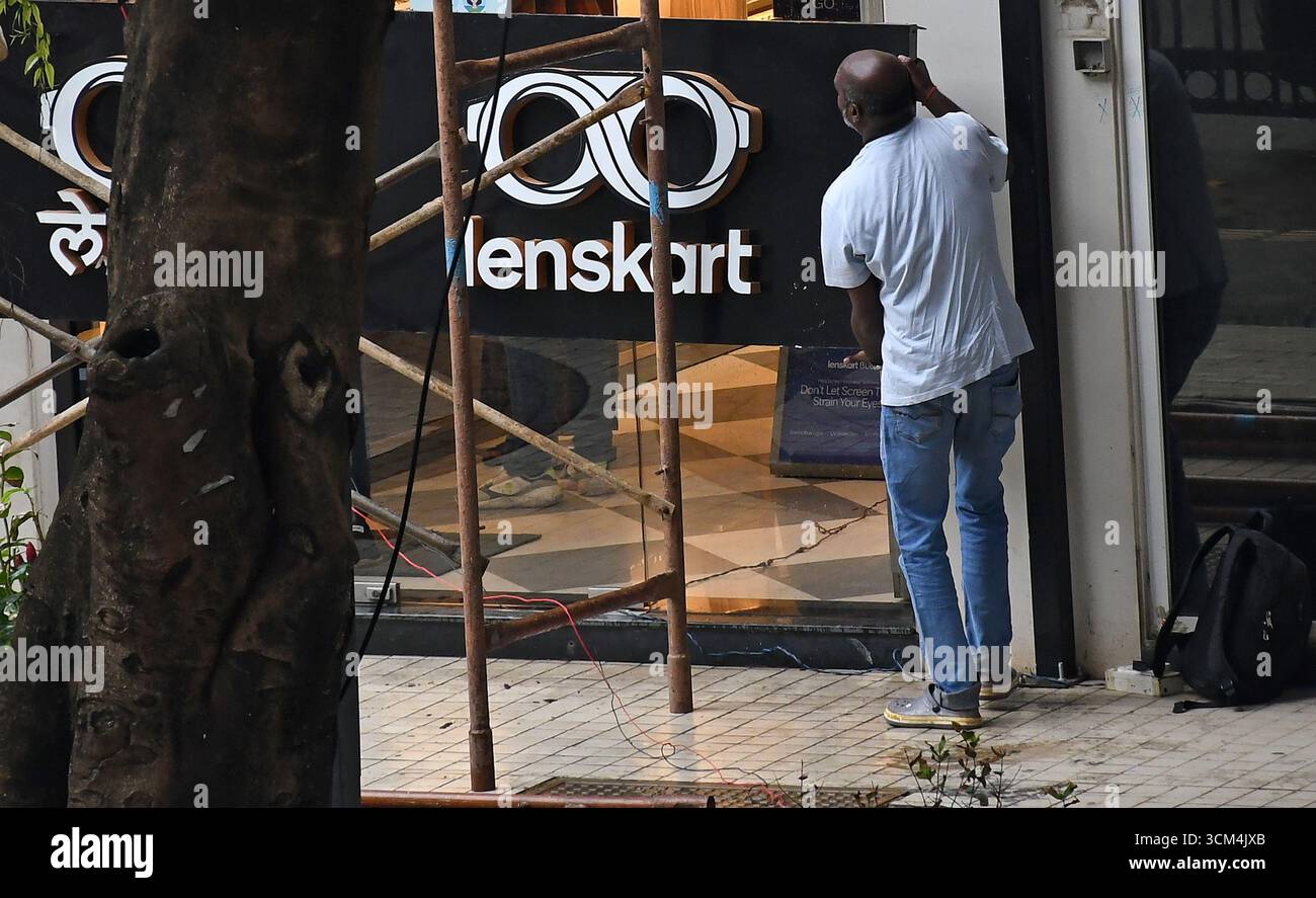 Ein Mann hält ein Schild von Lenskart, nachdem er es vor seinem Laden repariert hat. Lenskart ist eine indische multinationale Brillenmarke, die von dem ehemaligen Microsoft-Mitarbeiter Peyush Bansal zusammen mit Amit Chaudhary, Neha Bansal (Ehefrau von Peyush Bansal) und Sumeet Kapahi gegründet wurde. Das Unternehmen verfügt über mehr als 2000 Geschäfte im ganzen Land, die Brillen verkaufen, und auch online über seine Website und mobile App. Stockfoto