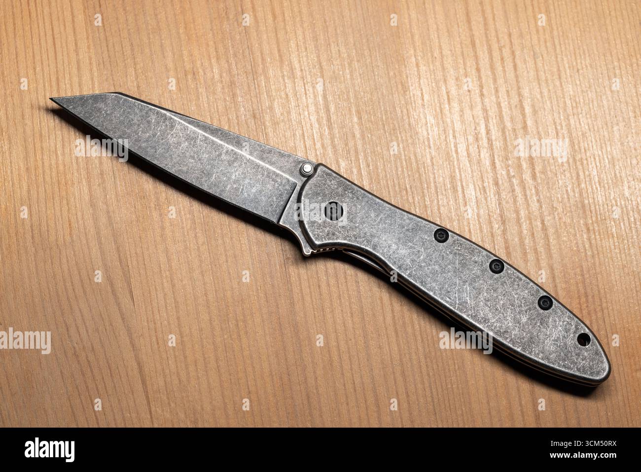 Detaillierte Ansicht eines modernen grauen Klappmessers aus Stahl mit schlankem Design auf Holztisch, Draufsicht Stockfoto