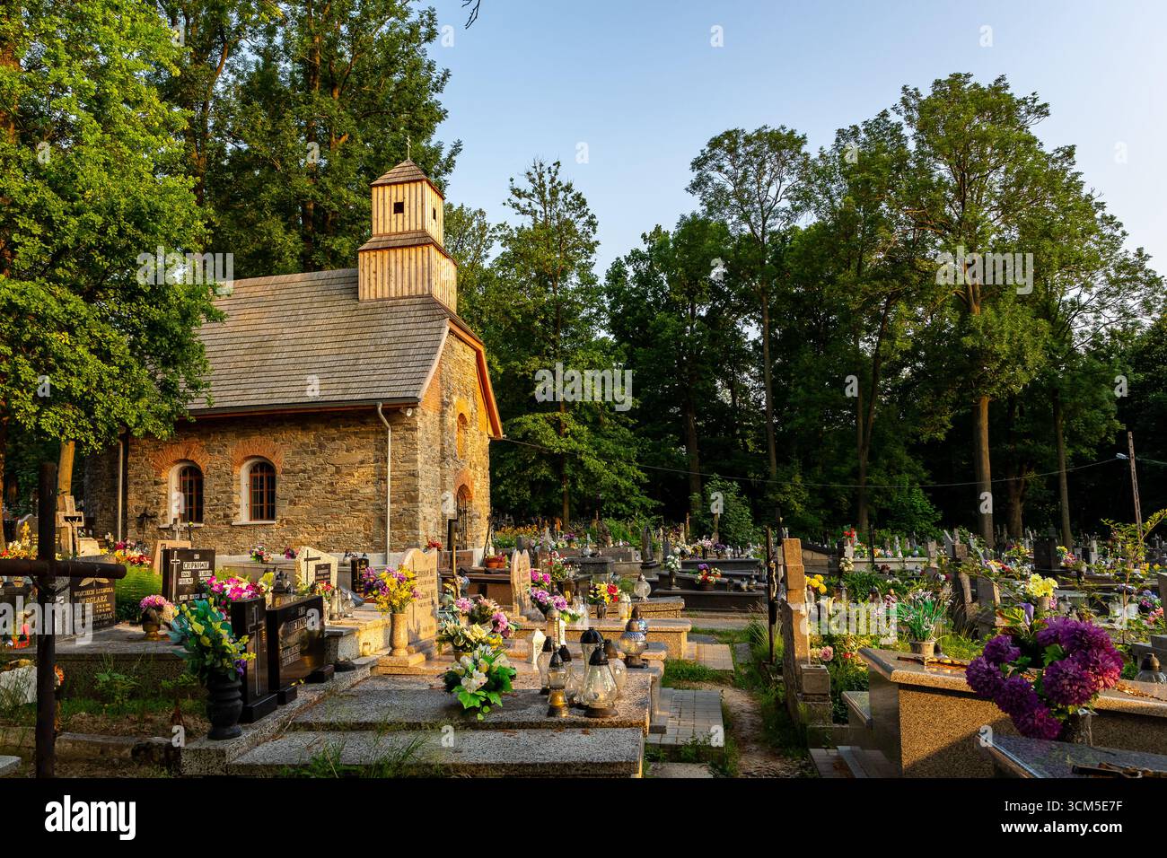 Milowka, Polen, 08.07.2021. Historische renovierte Backsteinkapelle, die der Heiligen Maria Magdalena auf dem Friedhof mit traditionell verzierten Gräbern gewidmet ist. Stockfoto
