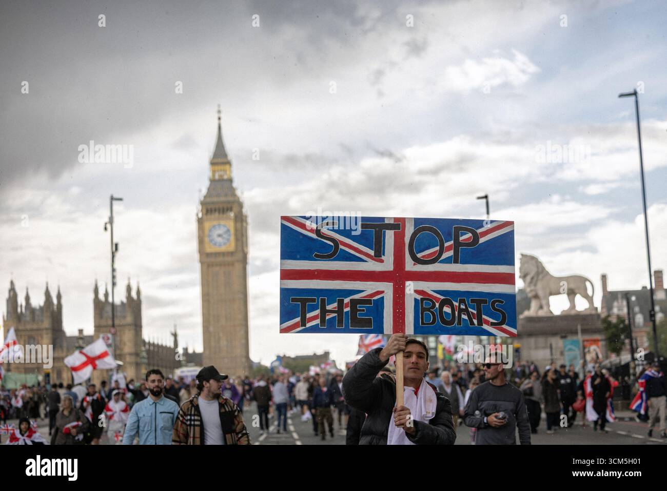 Ein Demonstrant der Unite the Kingdom-Rallye mit einem „Stop the Boats“-Schild während einer politischen Demonstration in London, Großbritannien. Stockfoto
