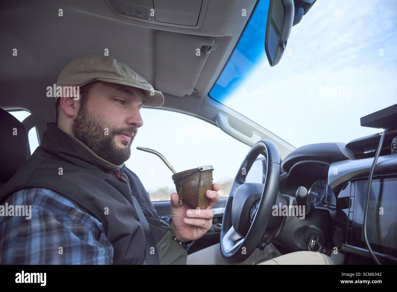 Mann, der ein Auto fährt, der während einer Pause auf der Straße einen Freund trinkt, während er durch Argentinien reist. Stockfoto