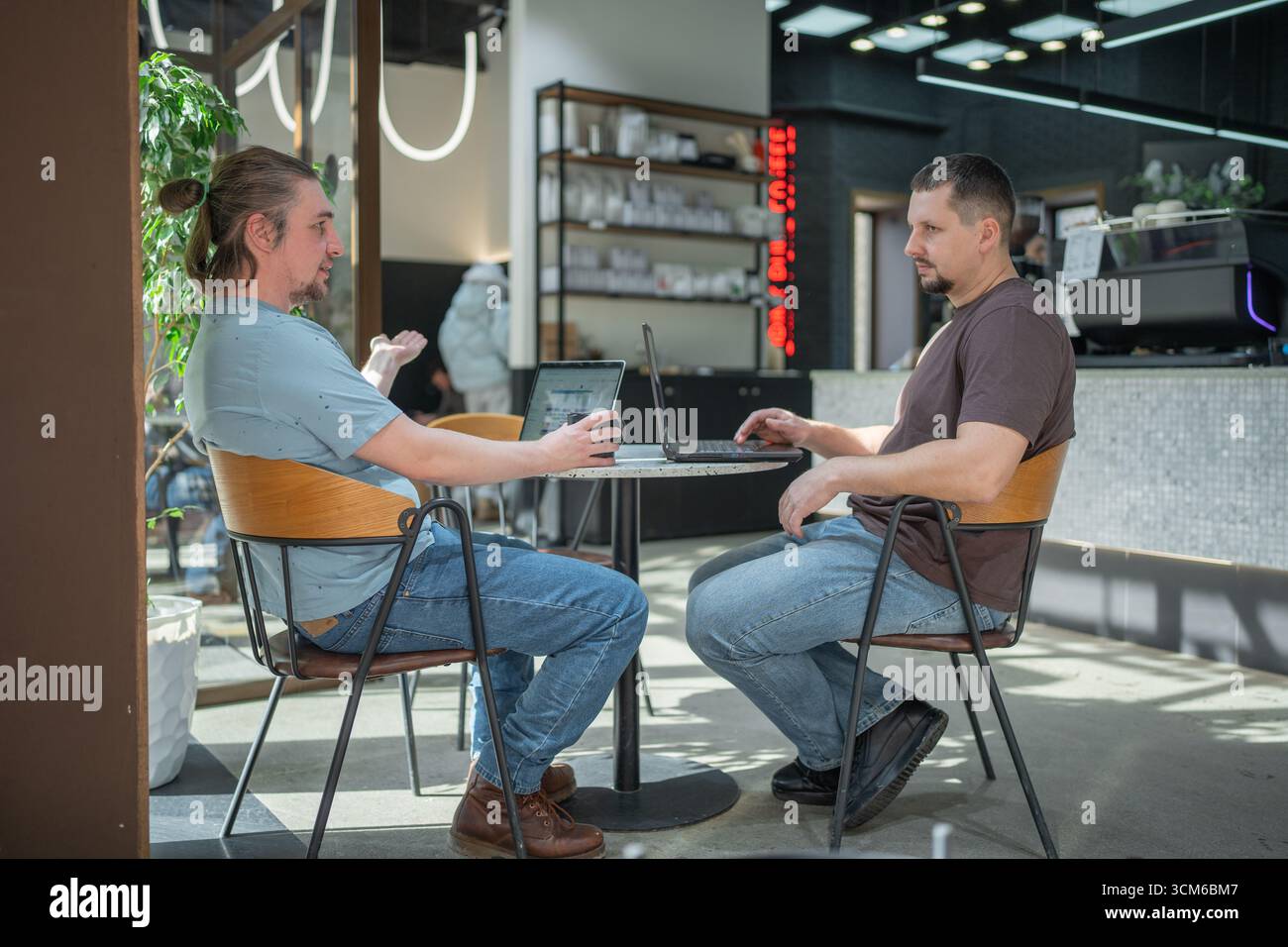 Zwangloses Meeting im modernen Café. Team von Programmierern, die digitalen Code in der Metaverse schreiben und zusammenarbeiten Stockfoto