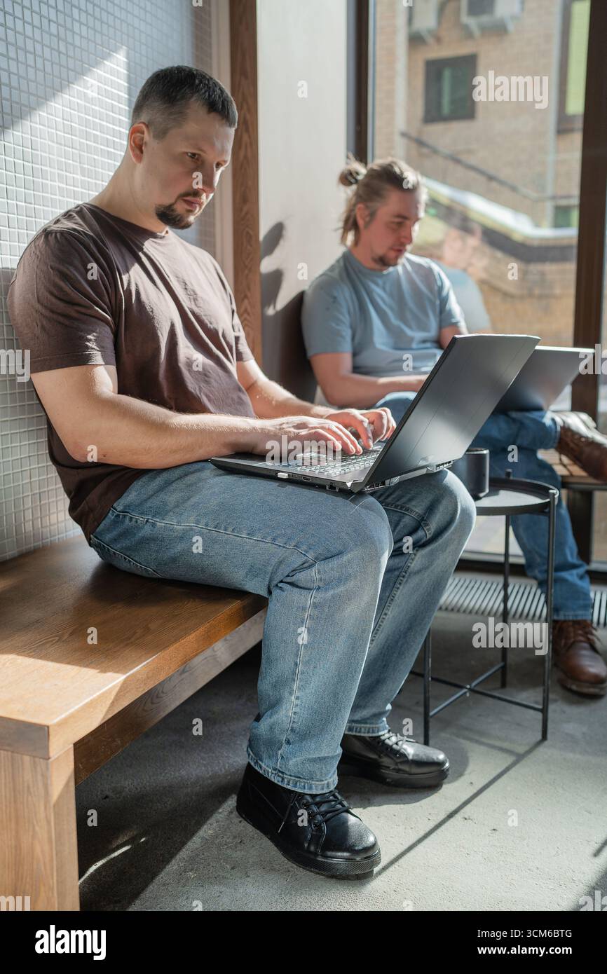 Zwangloses Meeting im modernen Café. Team von Programmierern, die digitalen Code in der Metaverse schreiben und zusammenarbeiten Stockfoto