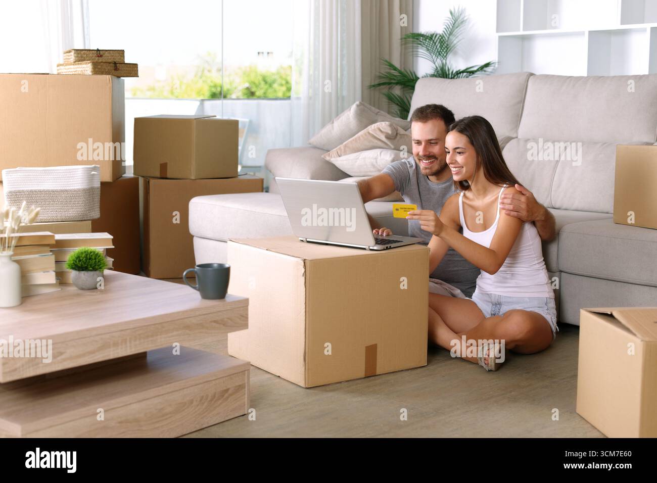 Glückliches Paar, das mit einem Laptop im Wohnzimmer nach Hause zieht Stockfoto