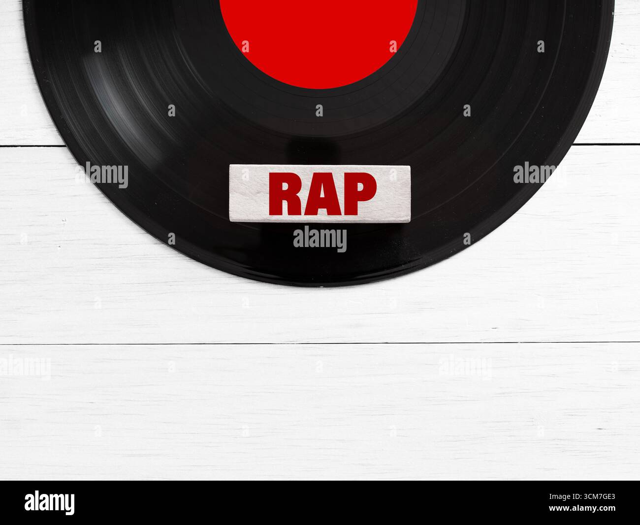 Schallplatte mit rotem Label und Rap-Musik-Genre-Fliese auf weißem hölzernem Hintergrund, die musikalisches Konzept repräsentiert Stockfoto