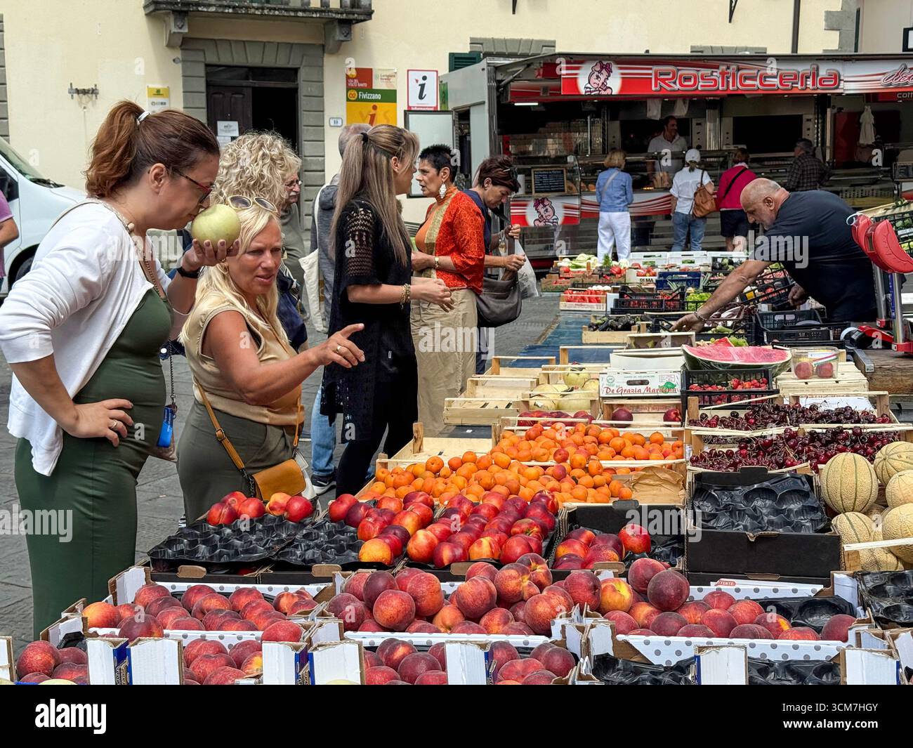 Ein geschäftiger Obst- und Gemüsestand auf dem Wochenmarkt auf der Piazza Medice aus dem 16. Jahrhundert in der mittelalterlichen Stadt Fivizzano, einer Gemeinde in der Provinz M. - Smartphone-aufgenommenes Stockfoto