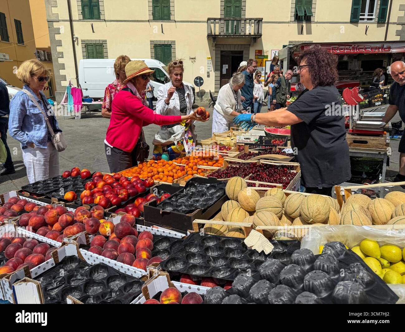 Ein geschäftiger Obst- und Gemüsestand auf dem Wochenmarkt auf der Piazza Medice aus dem 16. Jahrhundert in der mittelalterlichen Stadt Fivizzano, einer Gemeinde in der Provinz M. - Smartphone-aufgenommenes Stockfoto