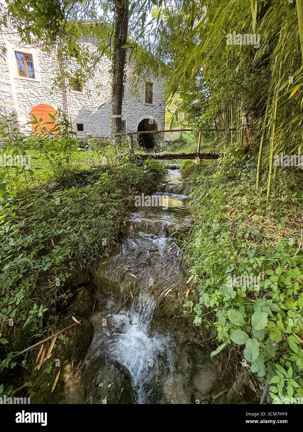 Ein schmaler Zufluss aus einer ehemaligen Wassermühle, der in den nahe gelegenen, flachen, felsigen Fluss Fiume Rosaro (Rosaro River) mündet, der am Weiler o vorbeifließt Stockfoto