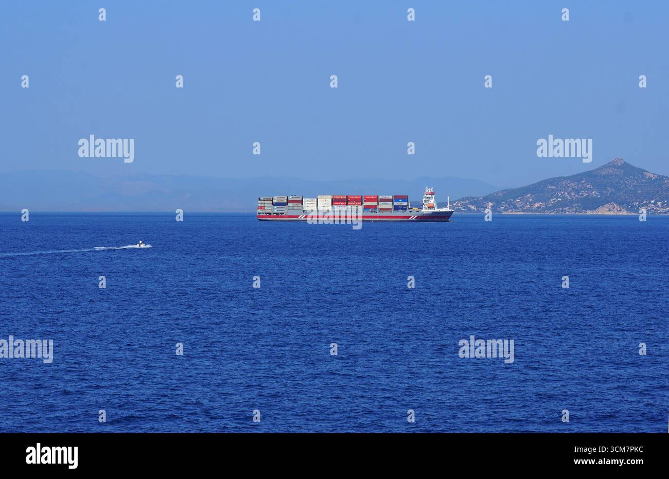 Ein mittelgroßes Containerschiff in der Nähe des Hafens von Piräus. Die Insel Salamis im Hintergrund Stockfoto