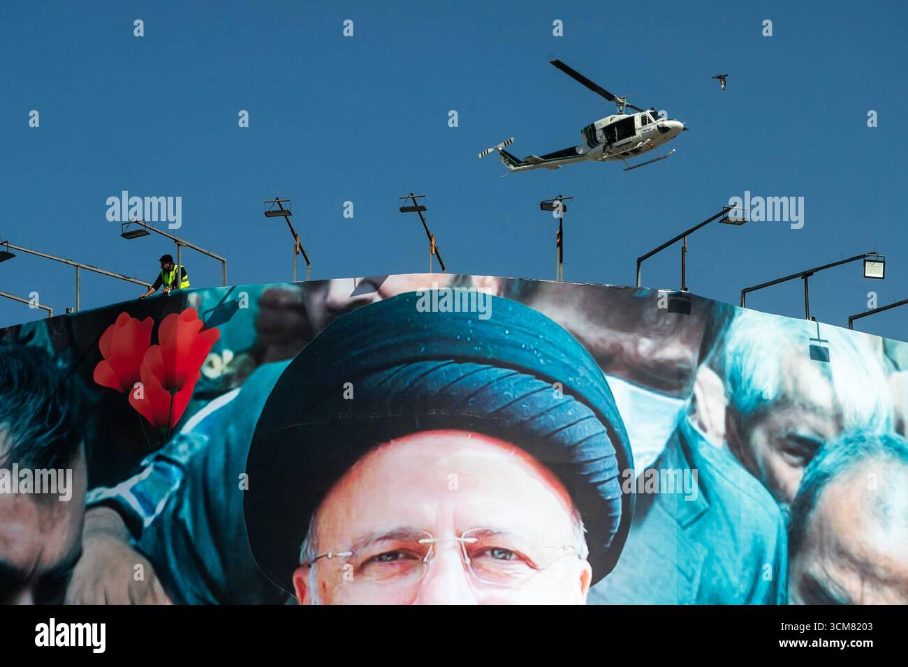 Teheran, Iran. Während seiner Beerdigung in Teheran fliegt ein Hubschrauber über einem Banner des verstorbenen Präsidenten Ebrahim Raisi. Raisi wurde bei einem Hubschrauberabsturz getötet Stockfoto