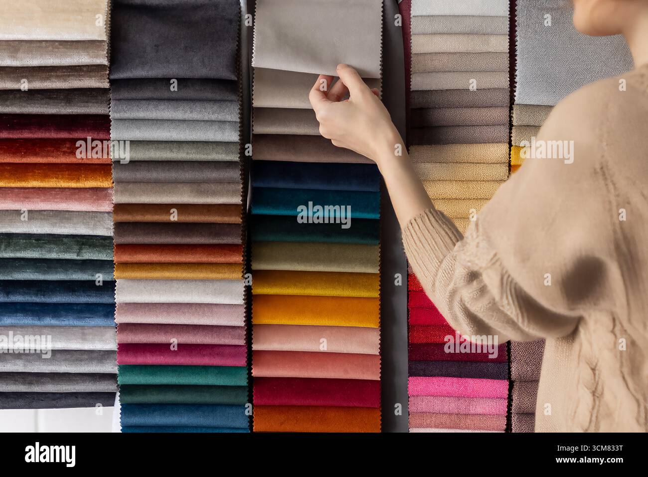 Eine Person, die Stoffe und Farben in einem Ausstellungsraum wählt. Ideal für Innenarchitektur, Beratung, Hausrenovierung Stockfoto