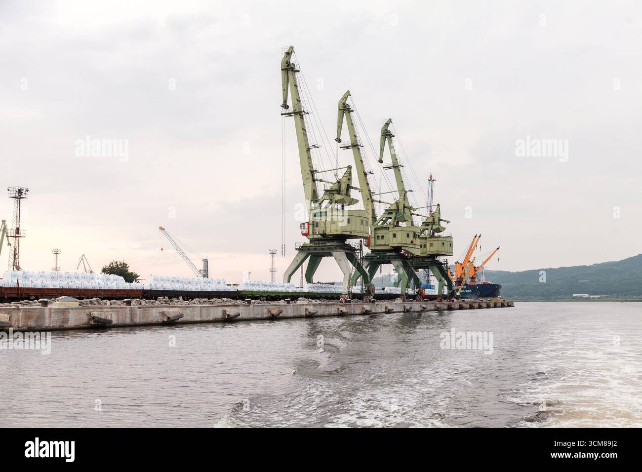 Varna, Bulgarien - 16. Juli 2014: Industrieanleger mit großen Portalkranen am Ufer mit Ladung, die den Transport und den Transport reflektieren Stockfoto
