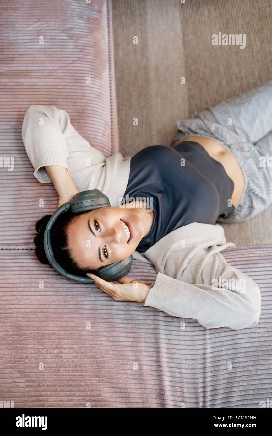 Frau, die sich zu Hause entspannt, Musik nach der Arbeit genießt. Stockfoto