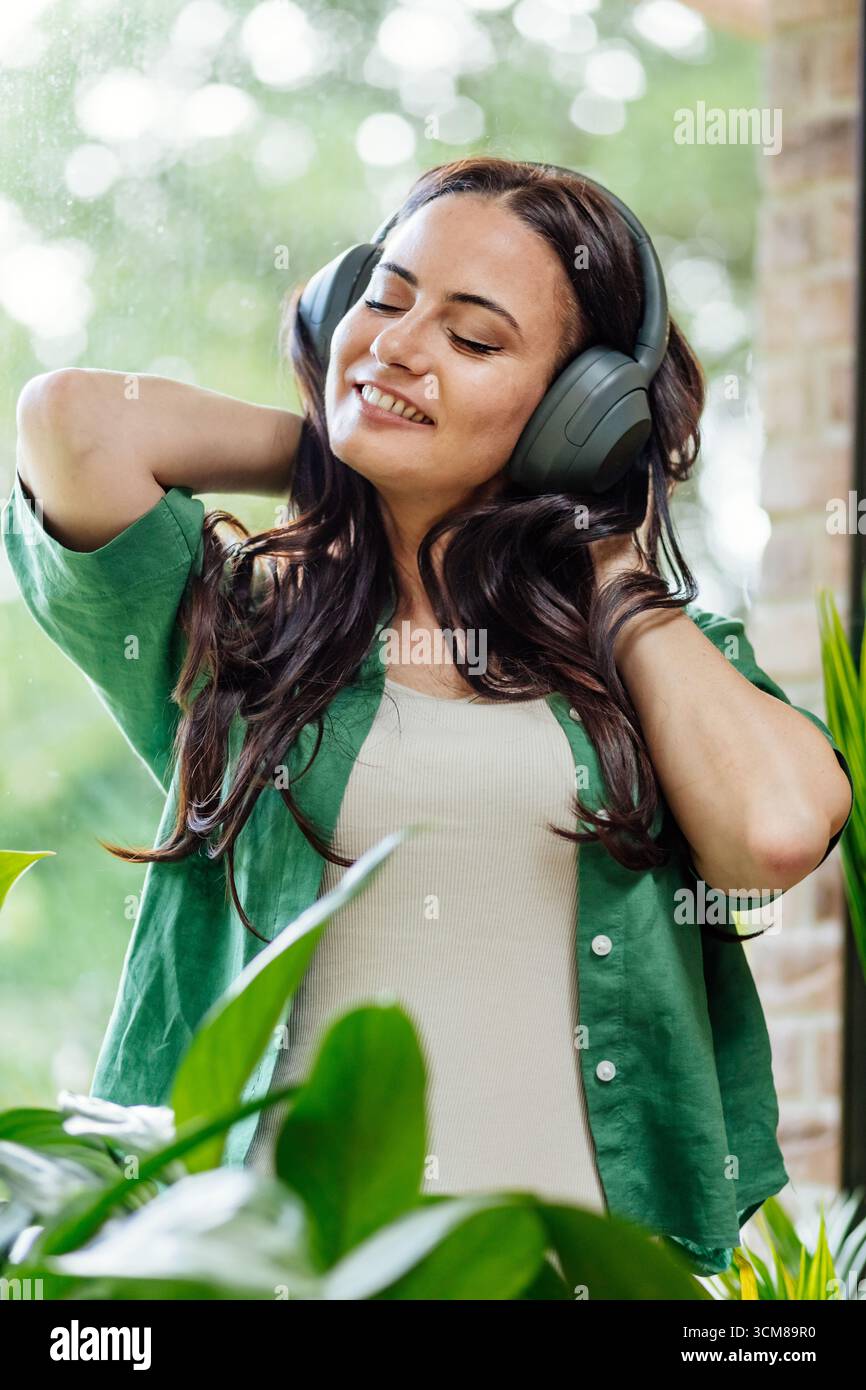 Entspannte Frau, die Freizeit genießt und Musik mit geschlossenen Augen hört. Stockfoto
