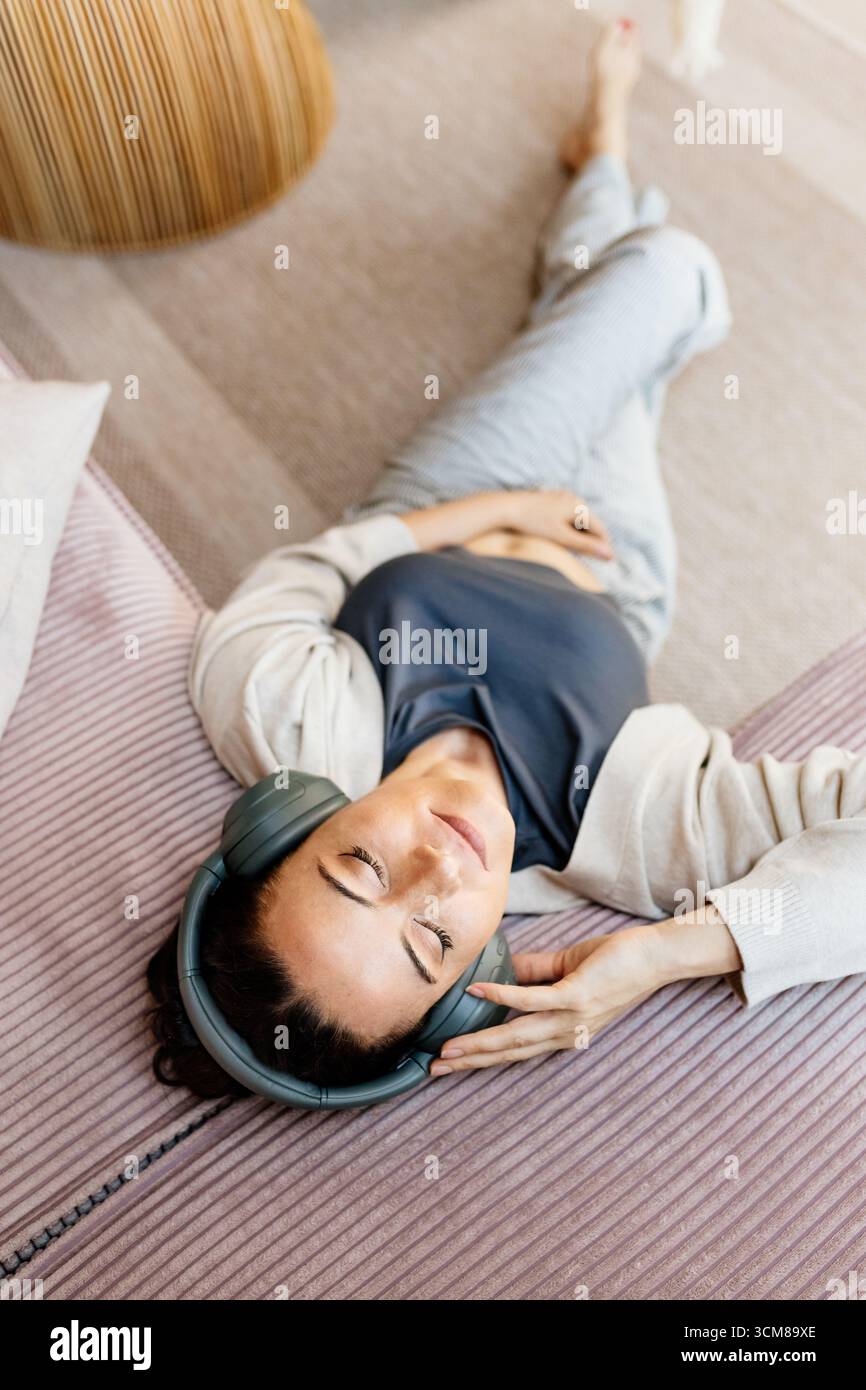 Frau, die sich zu Hause entspannt, Musik nach der Arbeit genießt. Stockfoto