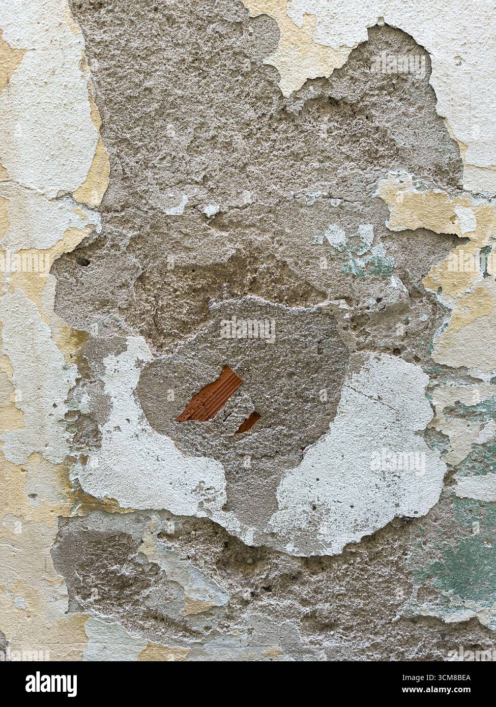 Nahaufnahme einer sich verschlechternden Putzwand mit Rissen, abblätternden Schichten und freiliegenden Ziegeln Stockfoto